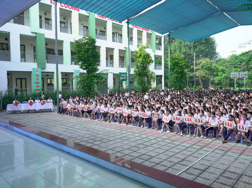 A large group of people sitting on a stage in front of a building

Description automatically generated with low confidence