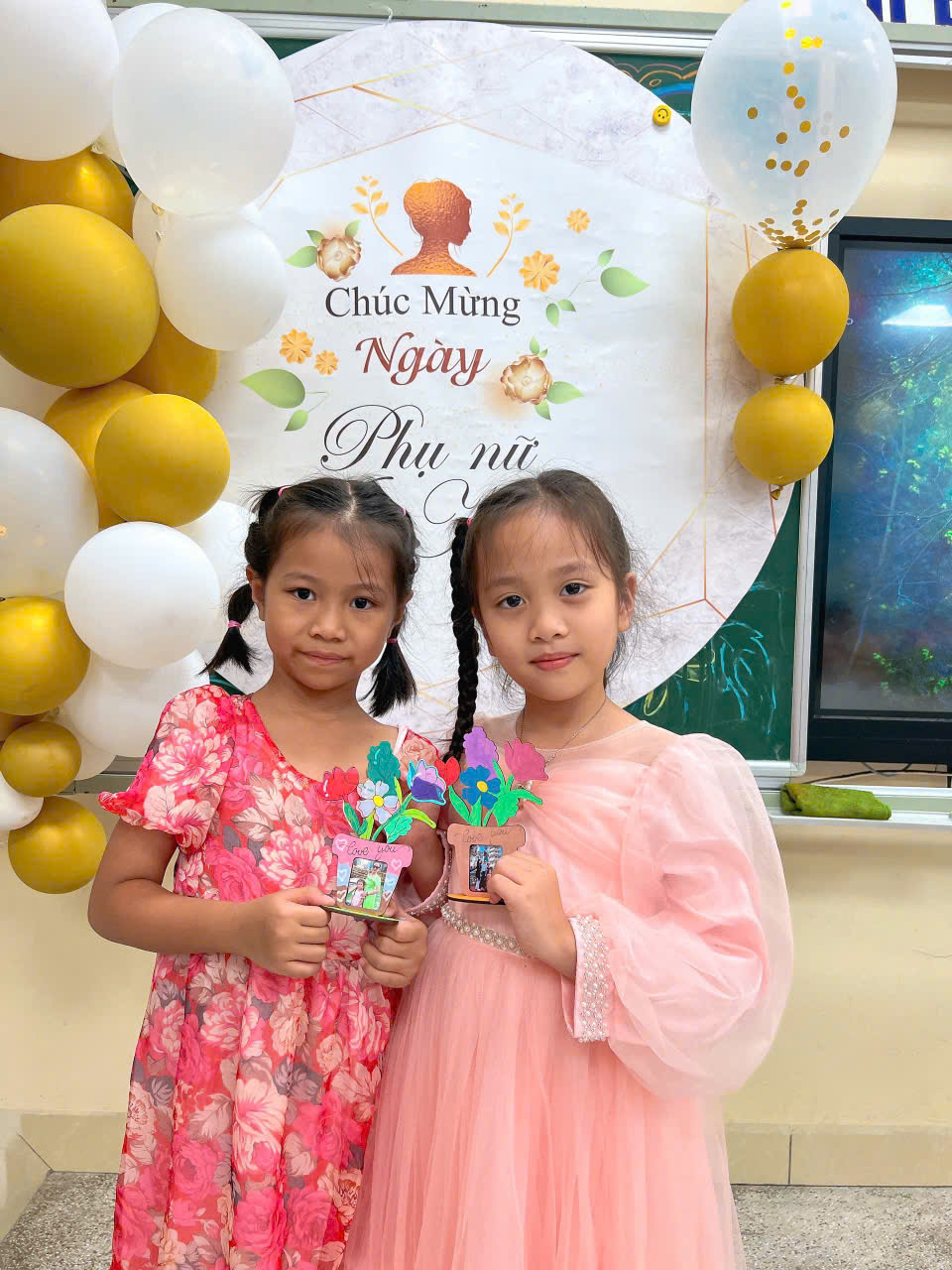 Two girls holding up small objectsDescription automatically generated