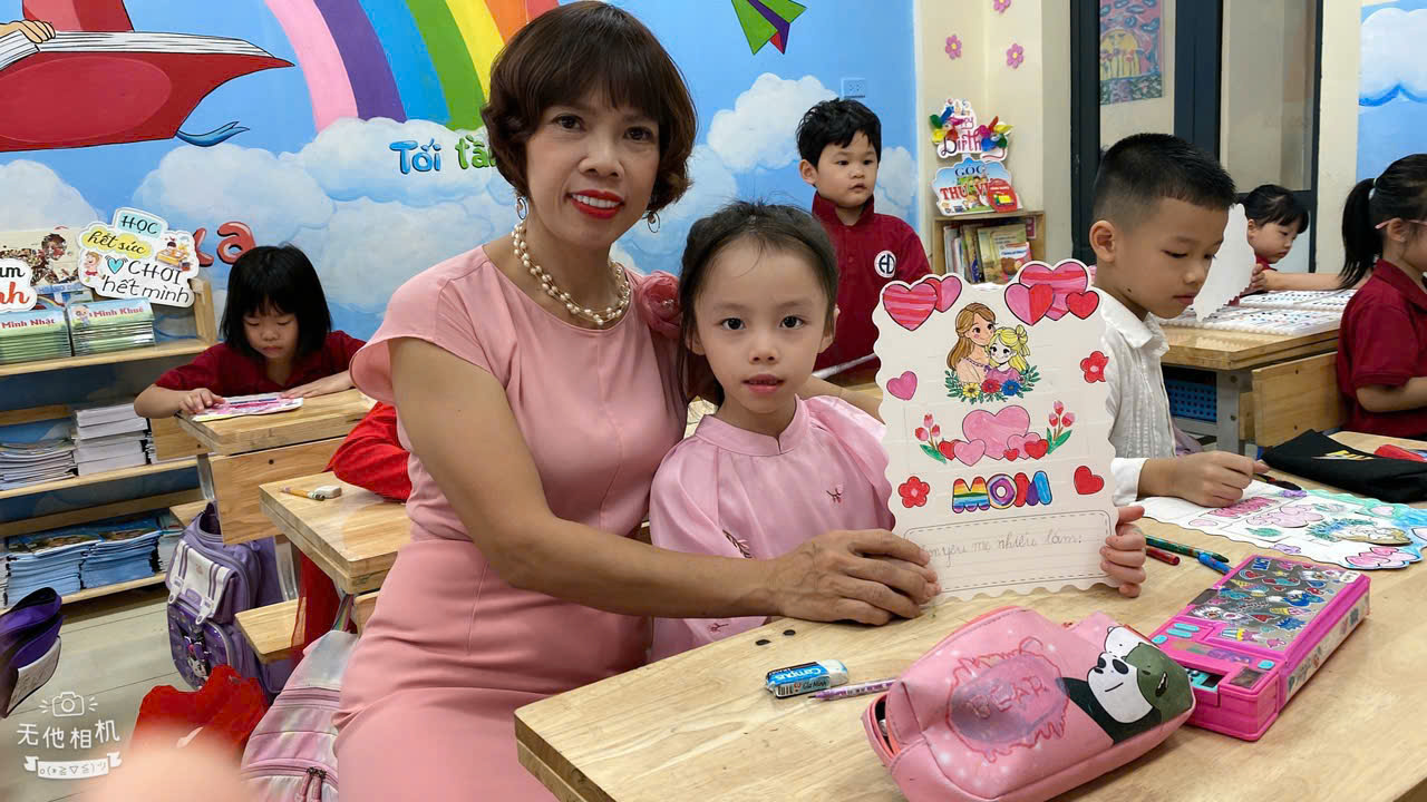 A person and a child sitting at a table with a picture of a bookDescription automatically generated