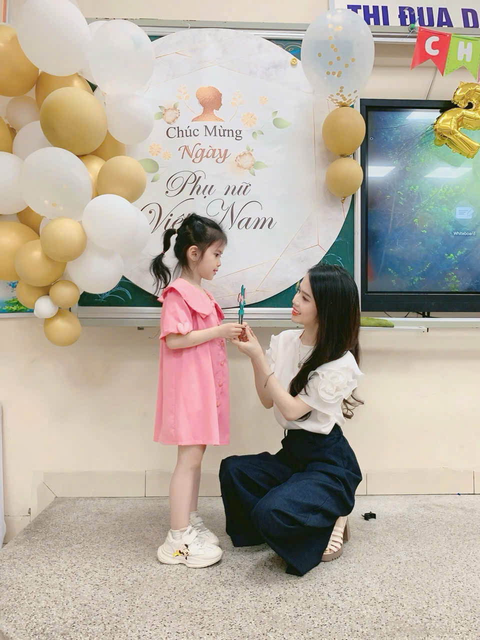 A person kneeling on the floor holding a child's handDescription automatically generated