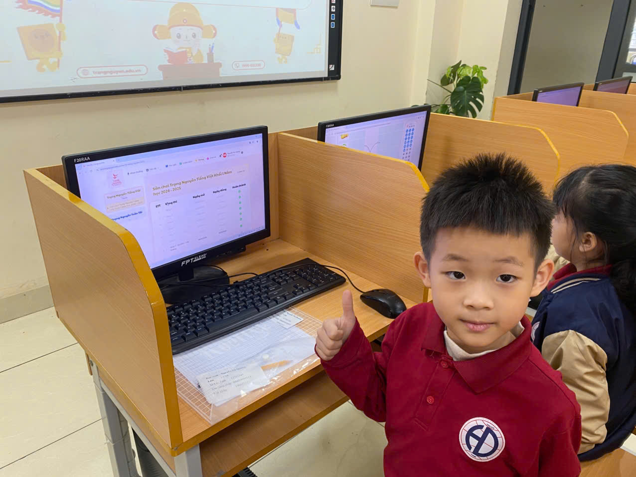 A child sitting at a desk with a computerDescription automatically generated