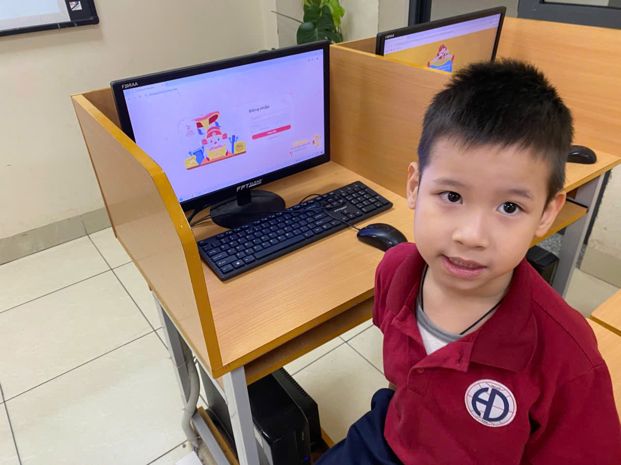 A child sitting at a desk with a computerDescription automatically generated