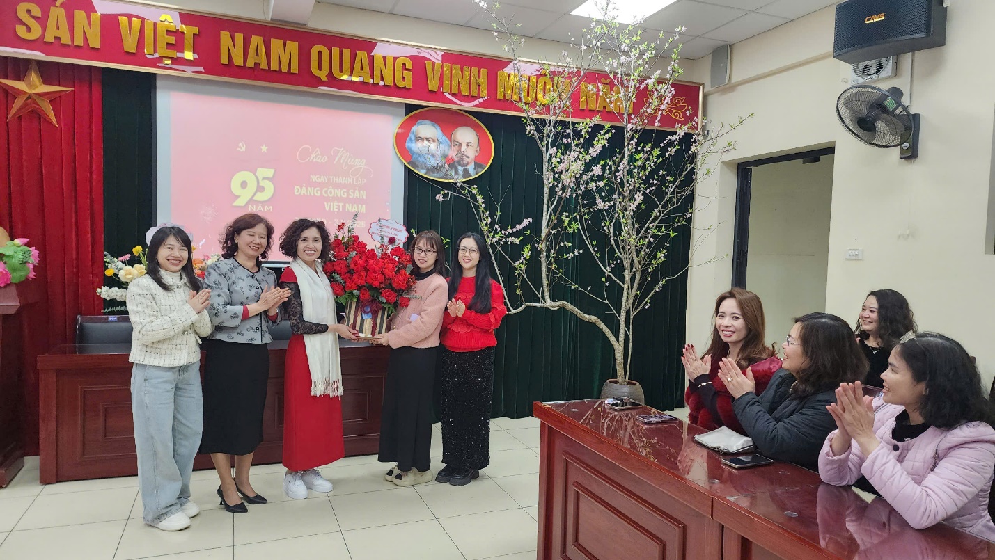A group of women standing in front of a desk

Description automatically generated