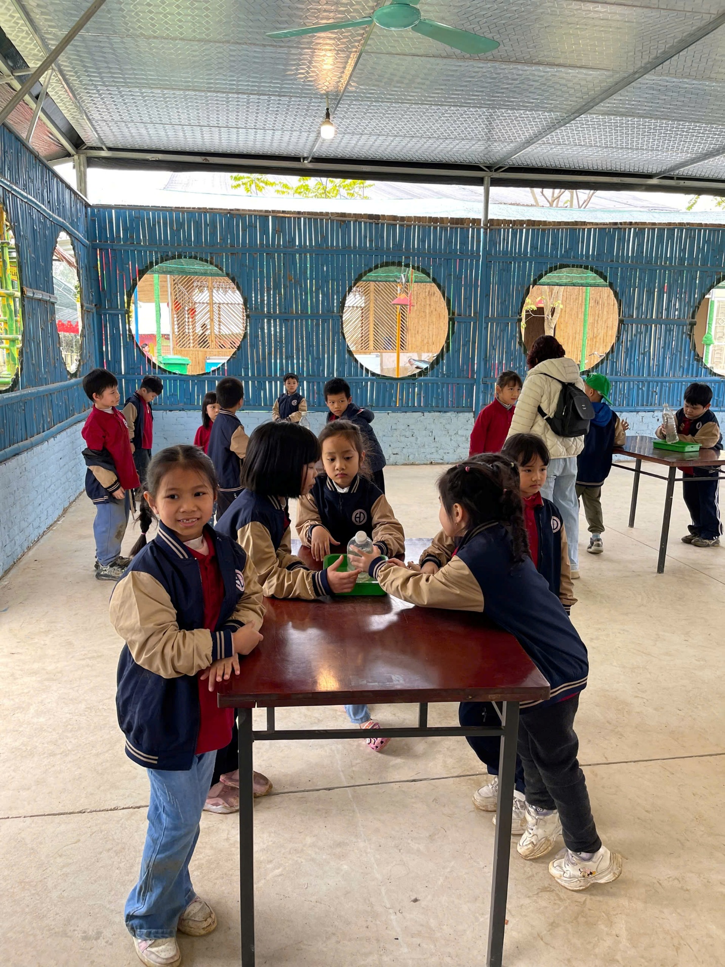 A group of children standing around a tableAI-generated content may be incorrect.