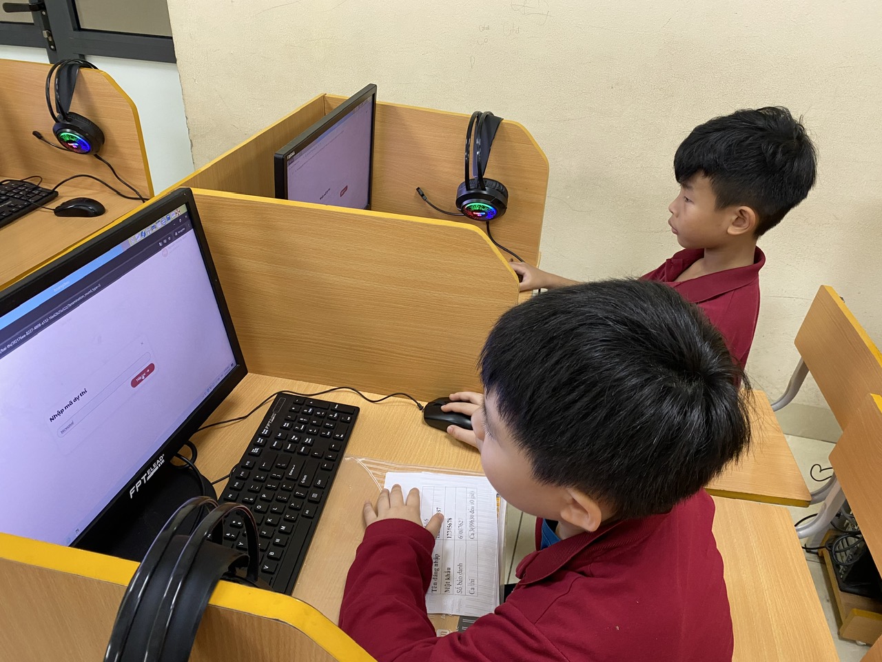 A group of kids sitting at a desk with computersAI-generated content may be incorrect.