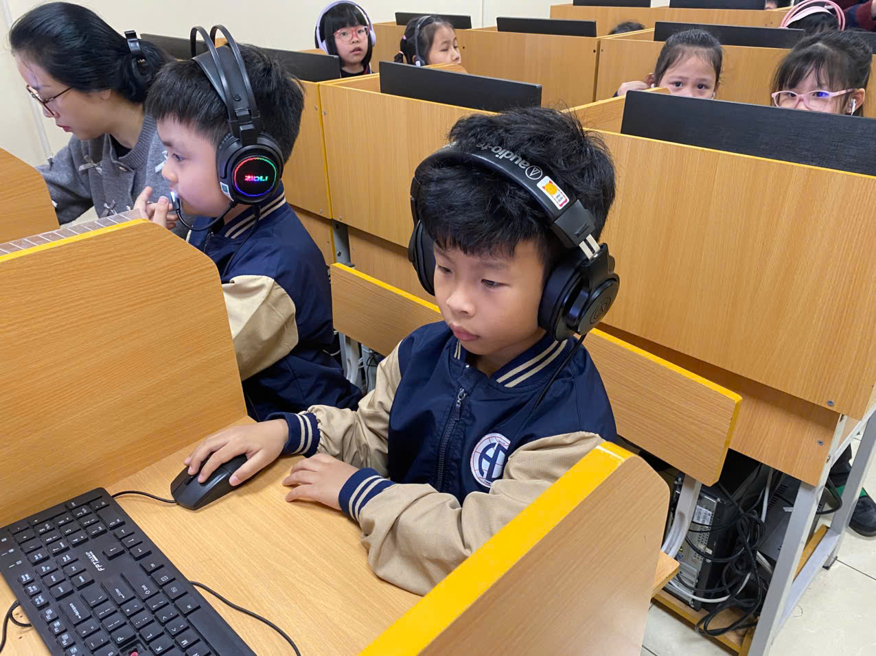 A group of kids wearing headphones and sitting at desksAI-generated content may be incorrect.