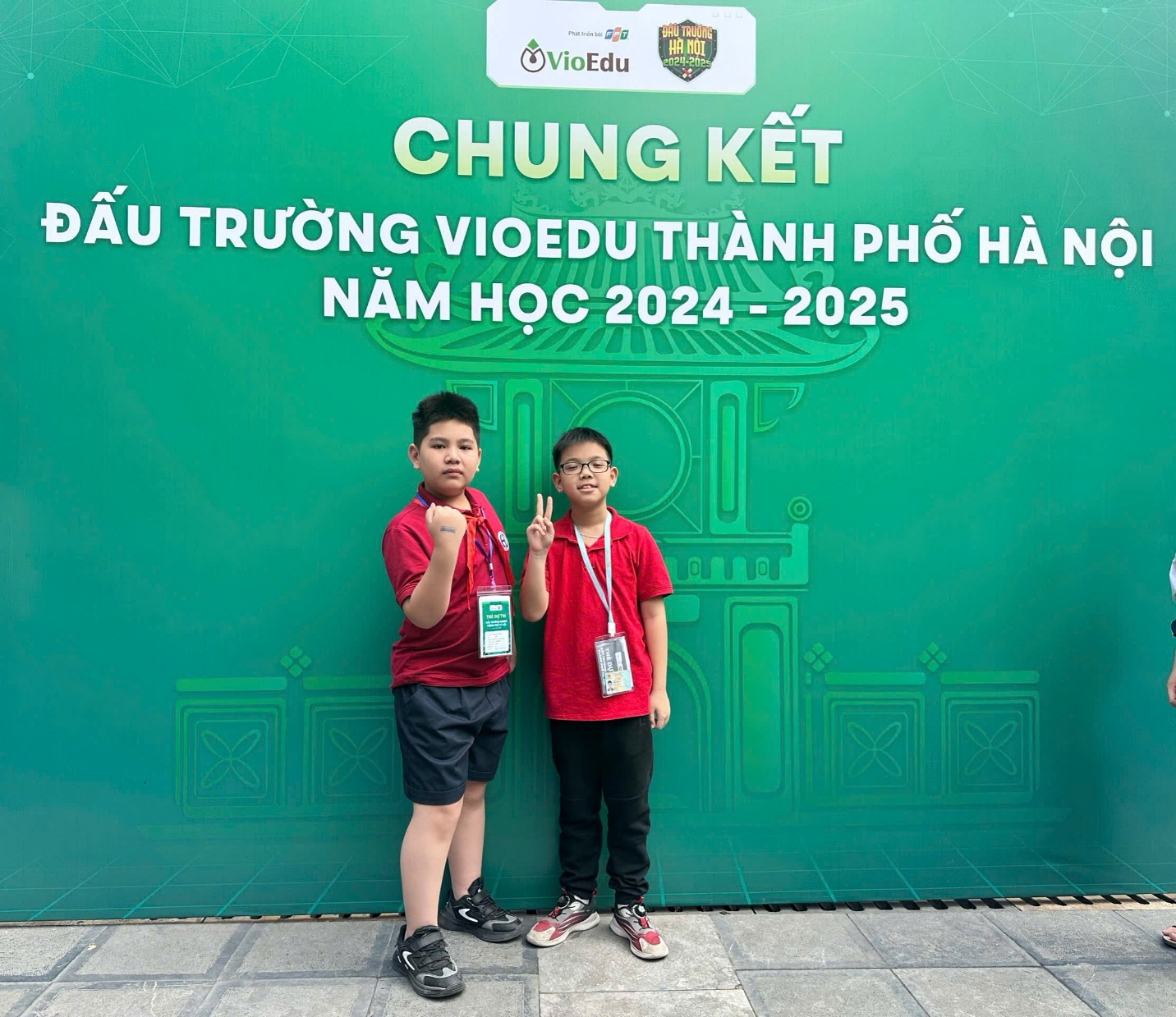 Two boys standing in front of a green signAI-generated content may be incorrect.