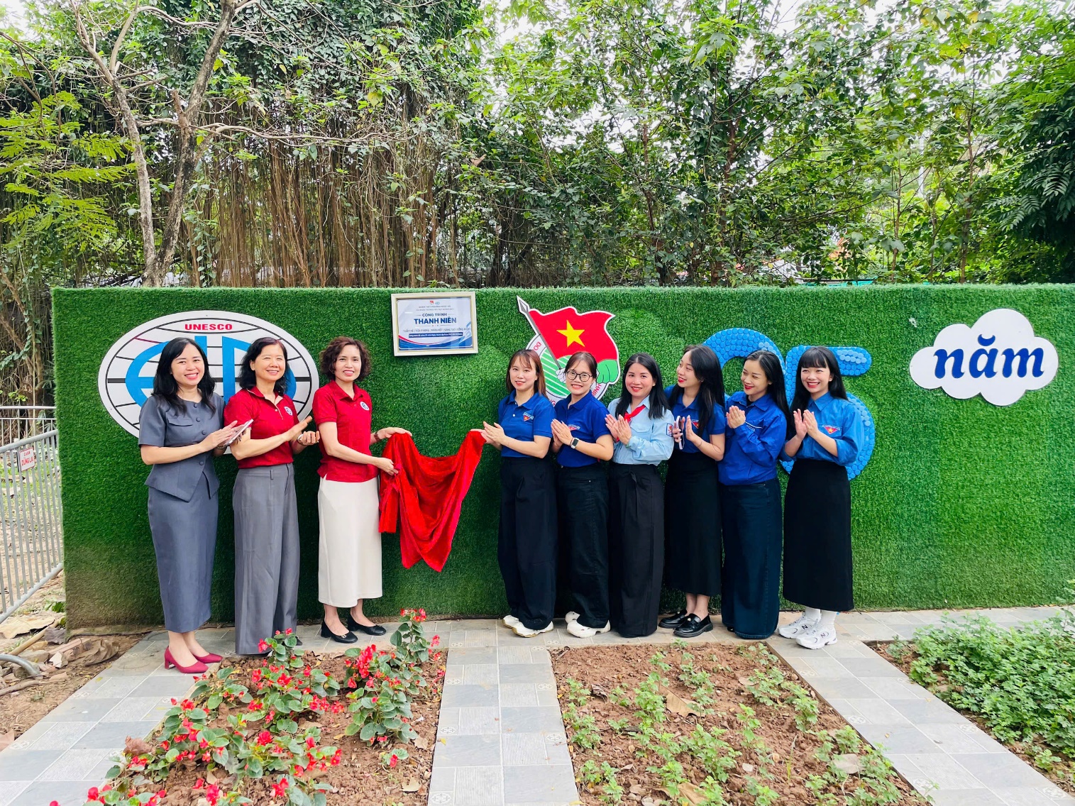 A group of women standing in front of a green wall

AI-generated content may be incorrect.