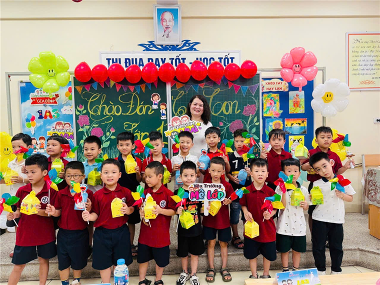 A group of children holding balloons and a teacher standing in front of a chalkboardAI-generated content may be incorrect.