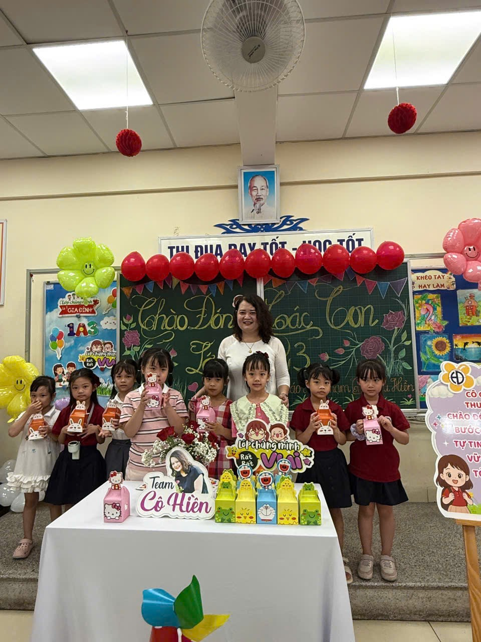 A group of children standing in front of a table with balloonsAI-generated content may be incorrect.