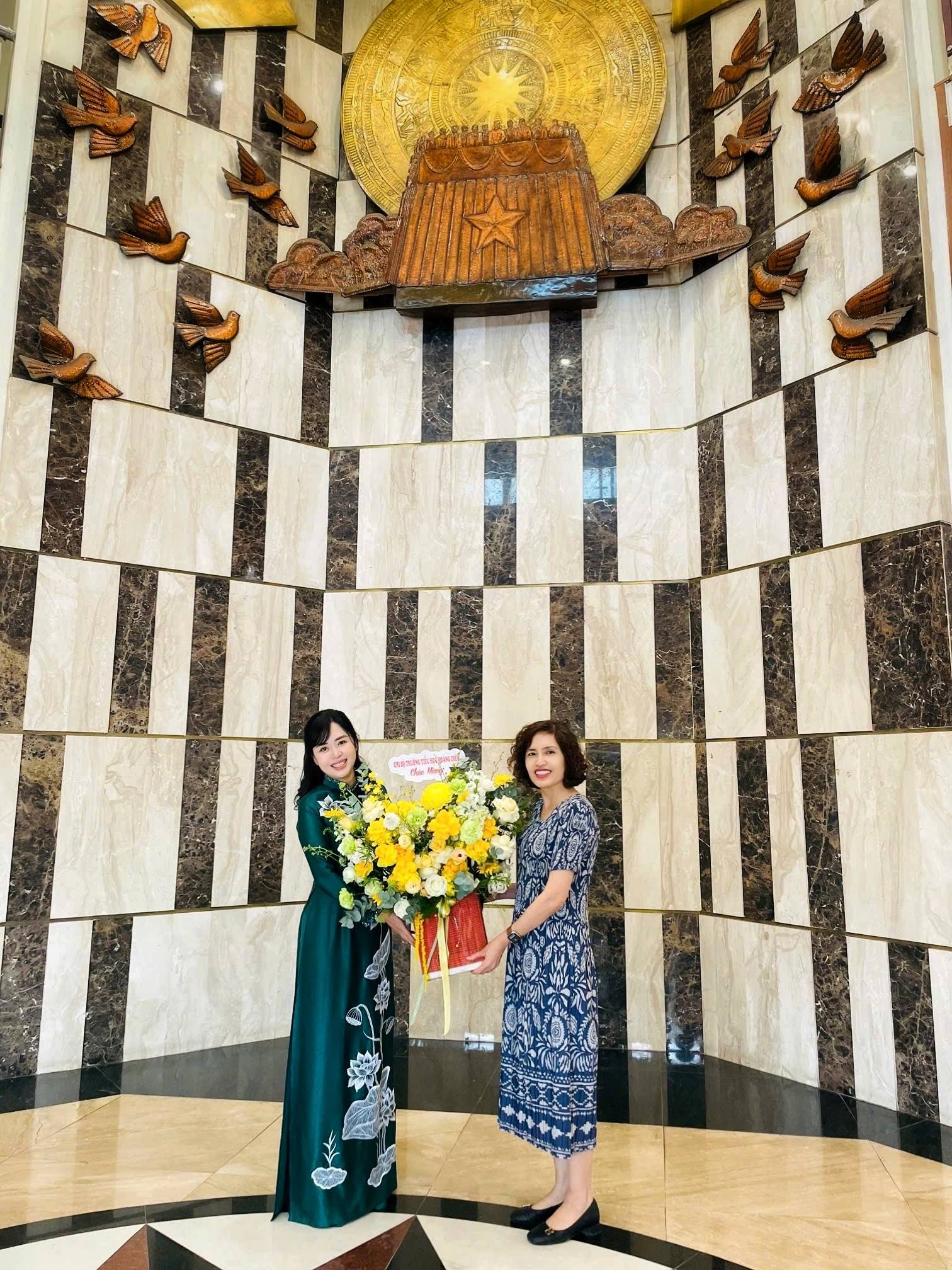 Two women standing in a room with a wall and a sculptureAI-generated content may be incorrect.